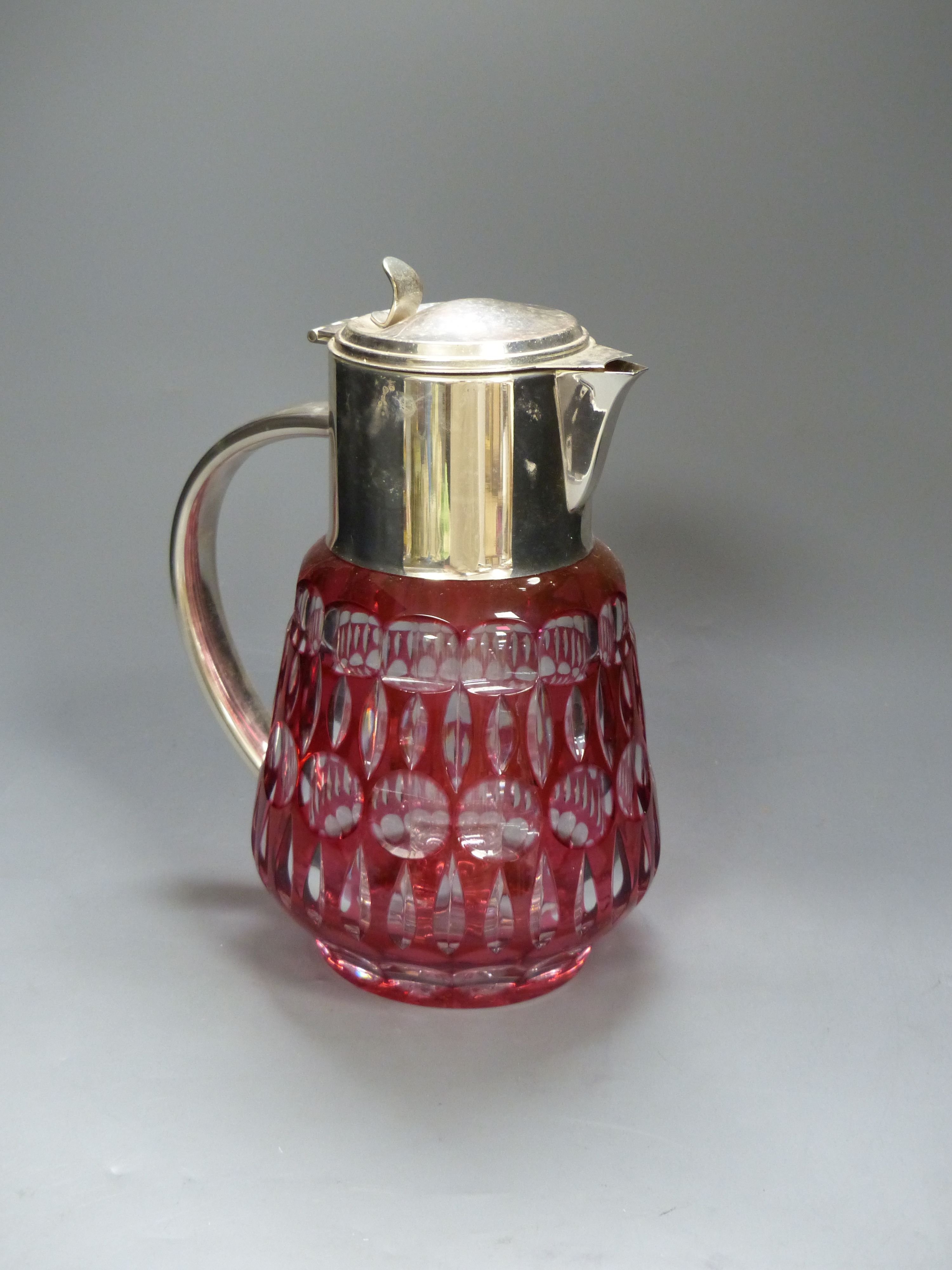 A large cranberry overlay cut glass lemonade jug with plated cover and handle, with removable ice tube, height 27cm